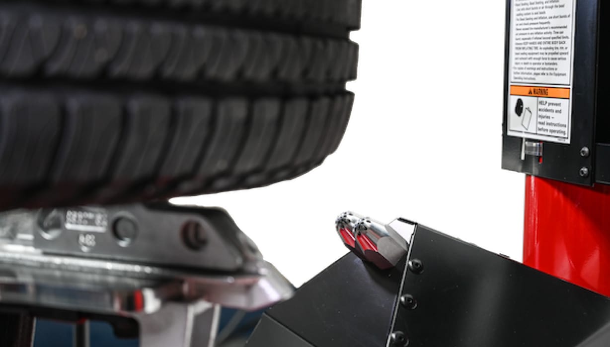2 bead sealing nozzles point at an upward angle toward a tire clamped on the tire changer