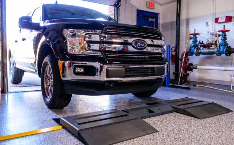 A Ford truck enters a garage and rolls over a Coats surface mount tread depth scanner