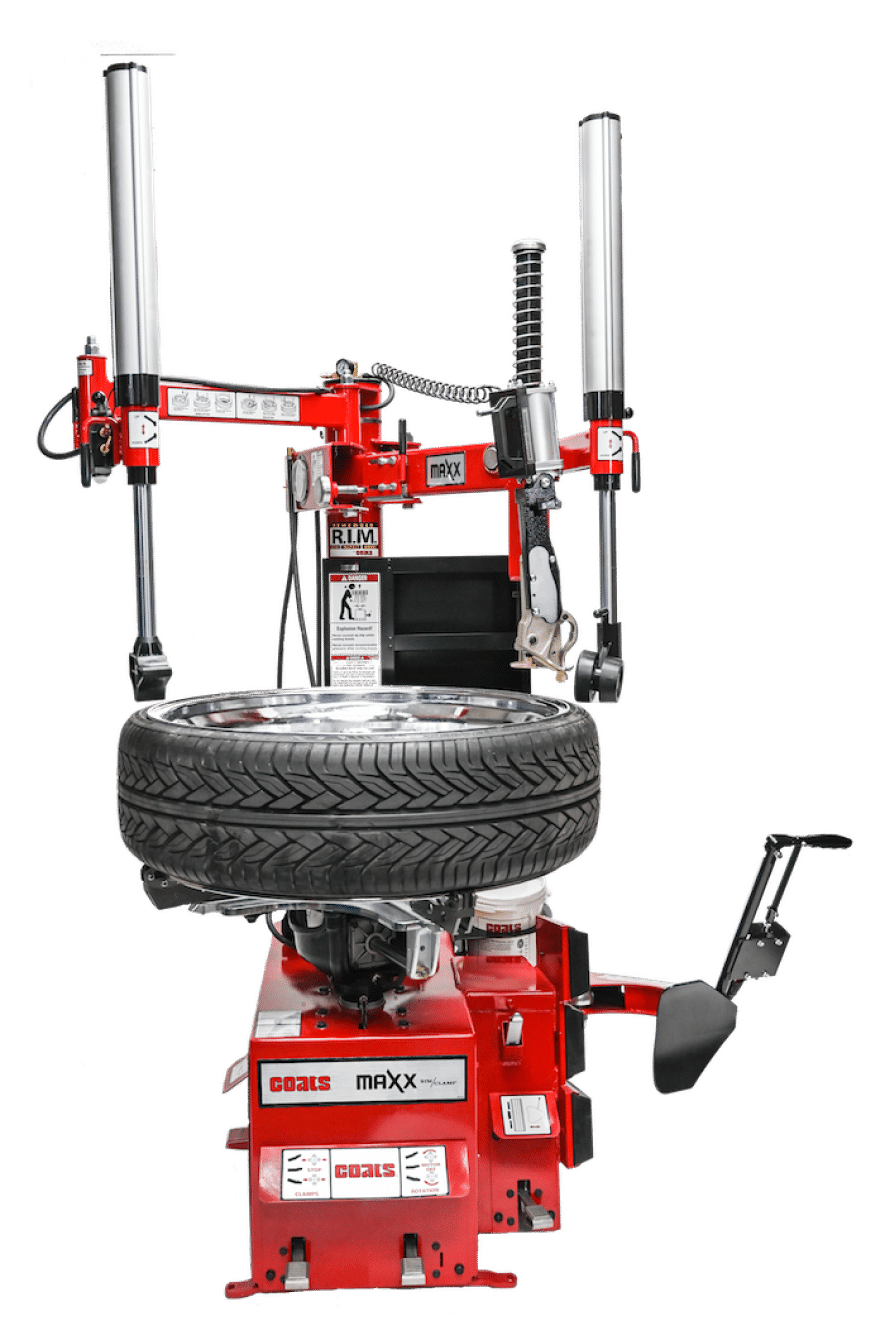 A red, Coats Maxx 90 tire changer with a large tire mounted on the table top
