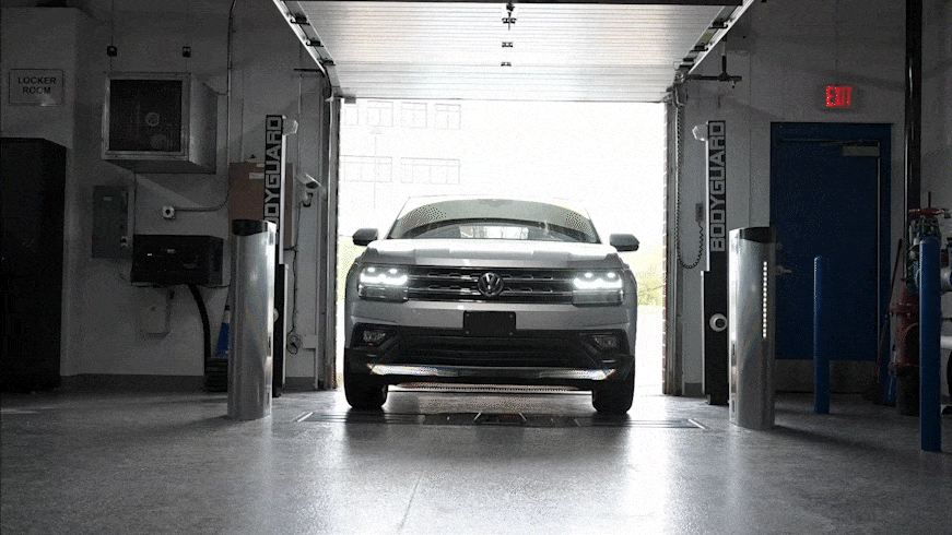 A silver Volkswagen SUV slowly pulls into a Coats inspection lane in a garage