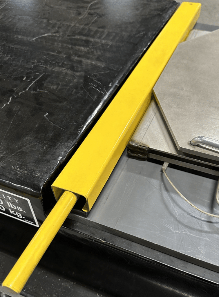 A yellow, metal tube placed in the gap between the lift's runway and front turn plate