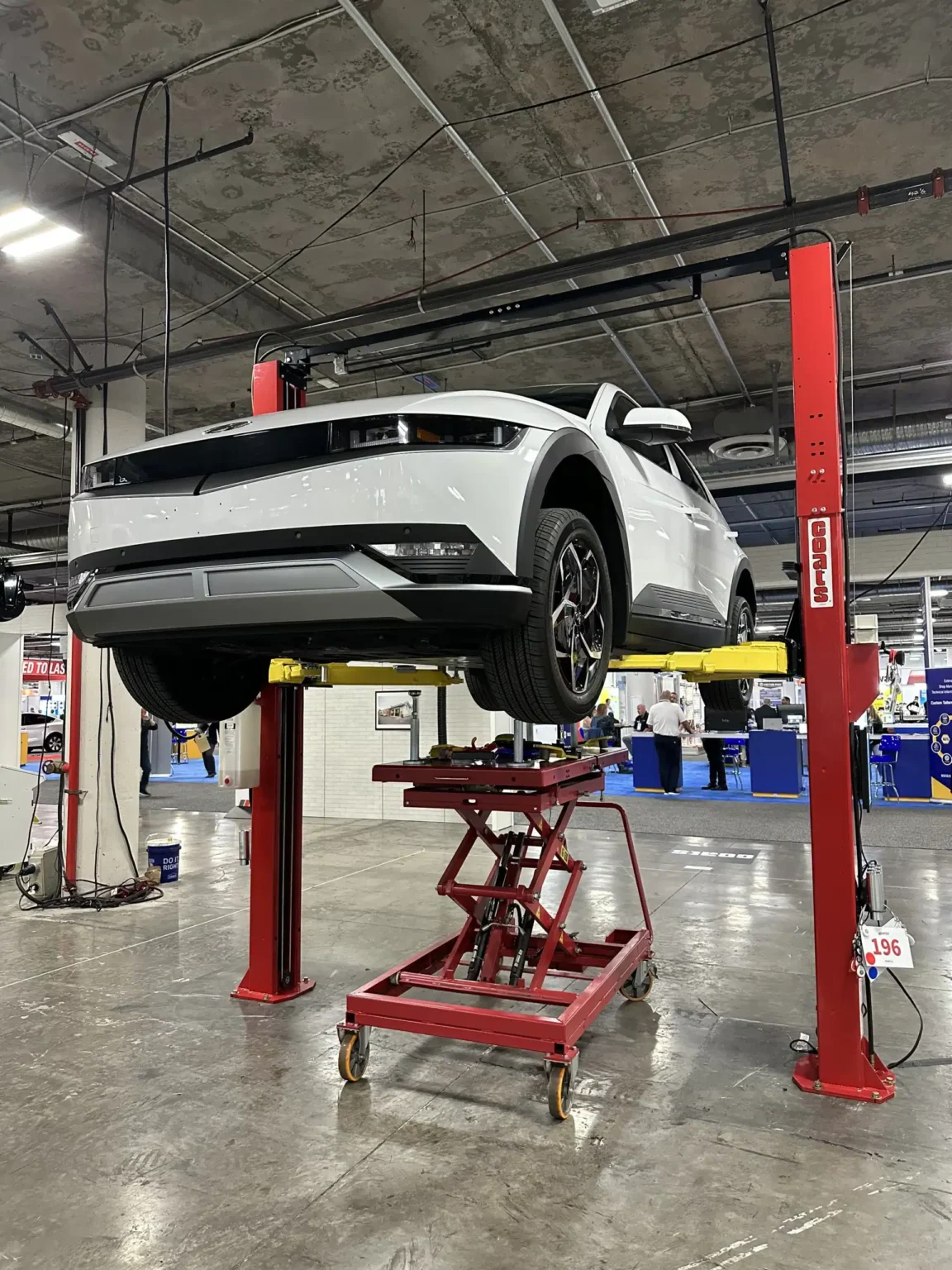 white suv lifted on a 2 post lift in a garage