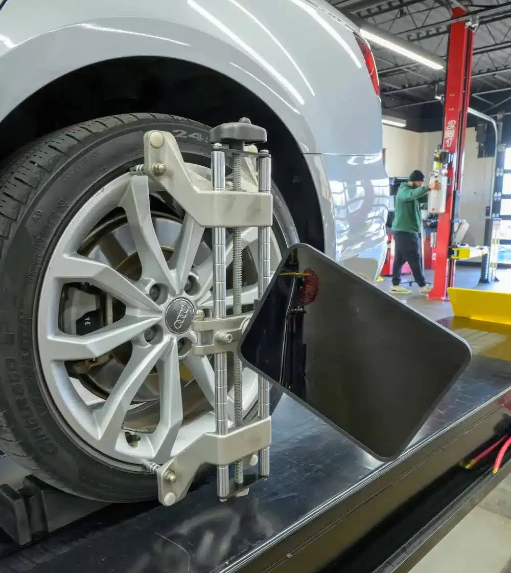 metal clamp with black diamond mini target attached in clamped onto the rim of a wheel of a car that's being aligned on a Coats alignment scissor lift