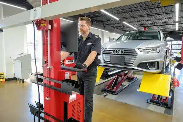 a man uses the monitor of the CWA6000 to perform an alignment on the silver sedan behind him, lifted on a Coats alignment scissor lift